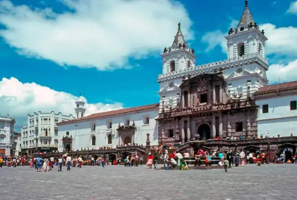 Crowd gathered in the main square in front of a white baroque church with twin towers.